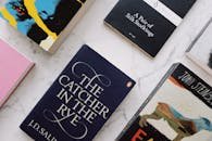Elegant flat lay of classic books including 'The Catcher in the Rye' on a marble surface.